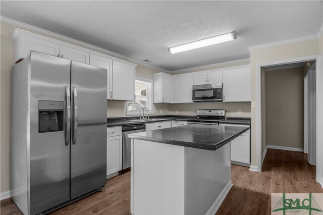 kitchen featuring stainless steel appliances, ornamental molding, a center island, and white cabinetry