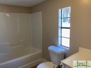 full bathroom with toilet, a healthy amount of sunlight, bathing tub / shower combination, and vanity