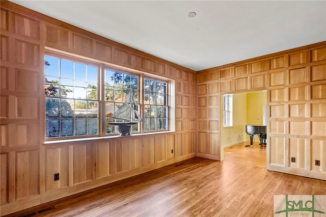 empty room with hardwood / wood-style floors and wooden walls