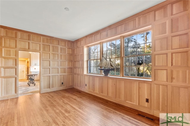 spare room with wooden walls and light hardwood / wood-style floors