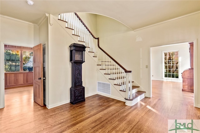 staircase featuring wood-type flooring and ornamental molding