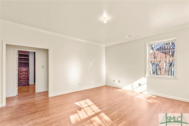 empty room with ornamental molding and light hardwood / wood-style floors