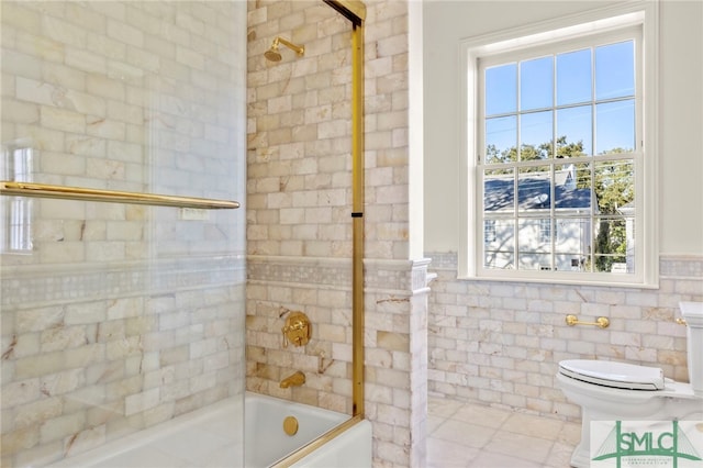 bathroom featuring bath / shower combo with glass door, tile walls, tile patterned floors, and toilet