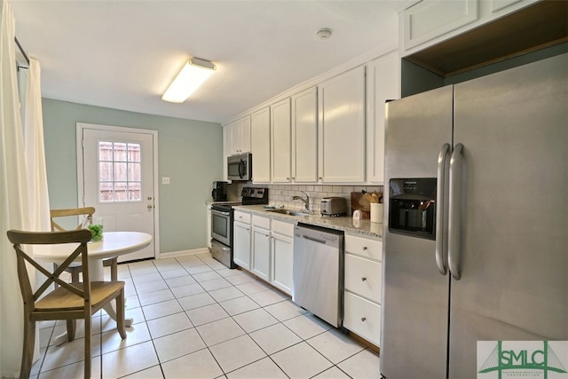 kitchen with stainless steel appliances, light tile flooring, white cabinetry, and sink