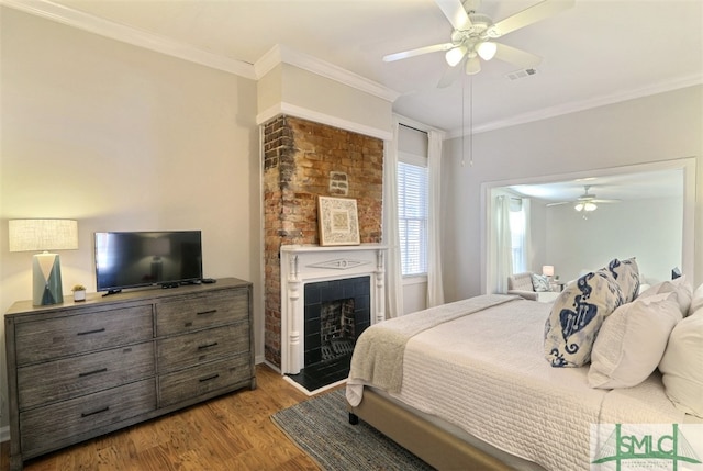 bedroom with a tiled fireplace, crown molding, ceiling fan, and light wood-type flooring