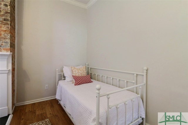 bedroom with ornamental molding, brick wall, and dark wood-type flooring