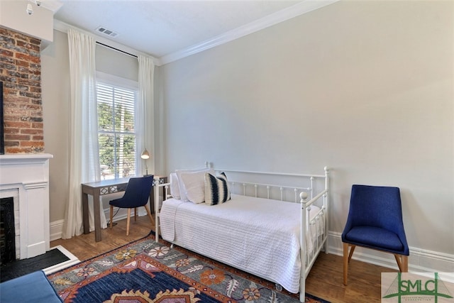 bedroom with crown molding, a fireplace, brick wall, and dark wood-type flooring