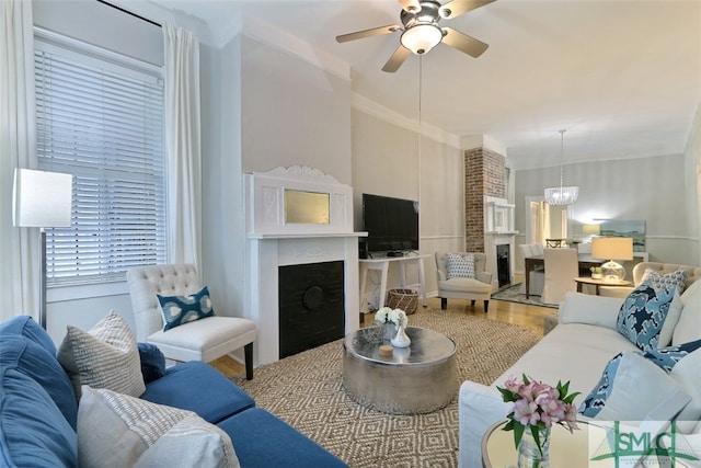 living room with brick wall, ornamental molding, ceiling fan with notable chandelier, and wood-type flooring