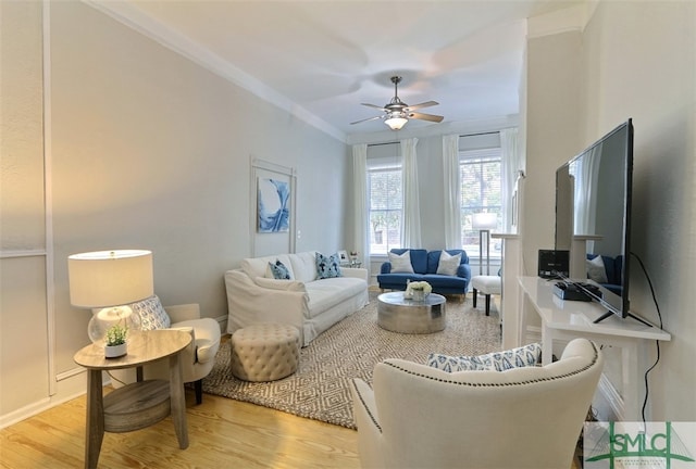 living room featuring light hardwood / wood-style floors, ornamental molding, and ceiling fan