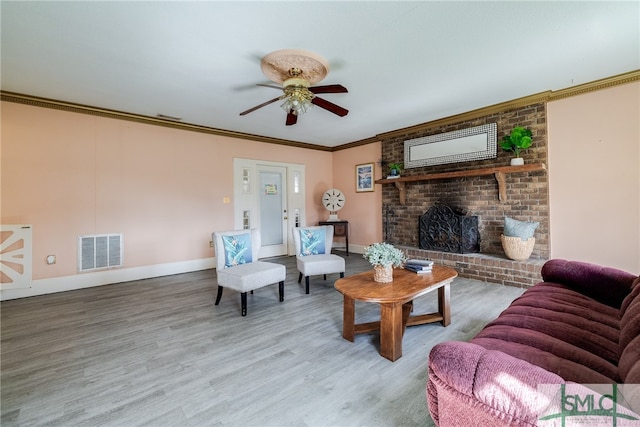 living room featuring ornamental molding, a brick fireplace, ceiling fan, and light wood-type flooring