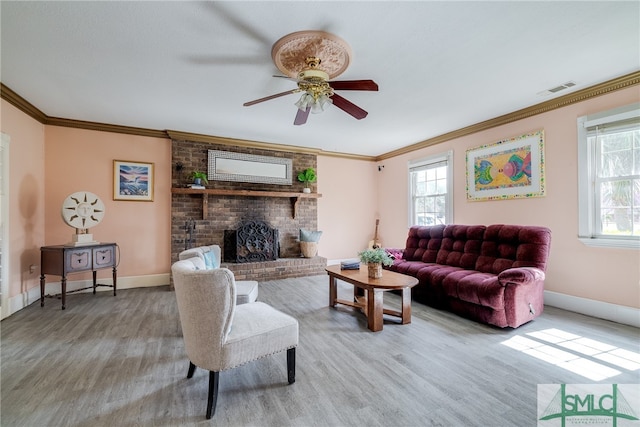 living room featuring light hardwood / wood-style floors, ceiling fan, a wealth of natural light, and a fireplace