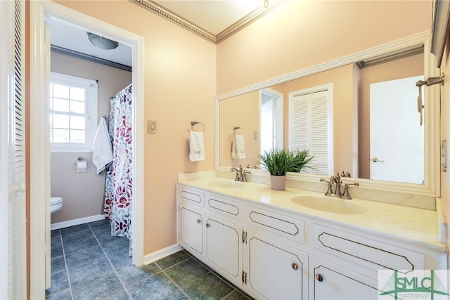 bathroom featuring tile floors, dual sinks, vanity with extensive cabinet space, toilet, and crown molding