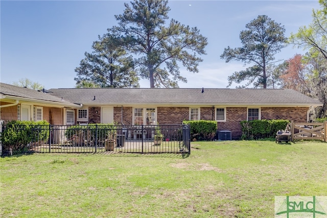 ranch-style house with central air condition unit and a front lawn