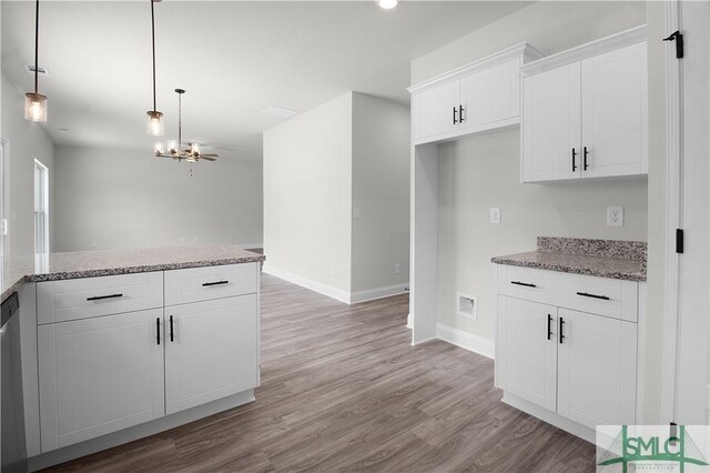 kitchen featuring white cabinets, stone counters, hanging light fixtures, and light hardwood / wood-style flooring