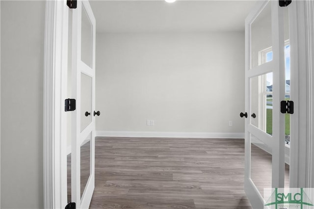 empty room featuring baseboards, wood finished floors, and french doors