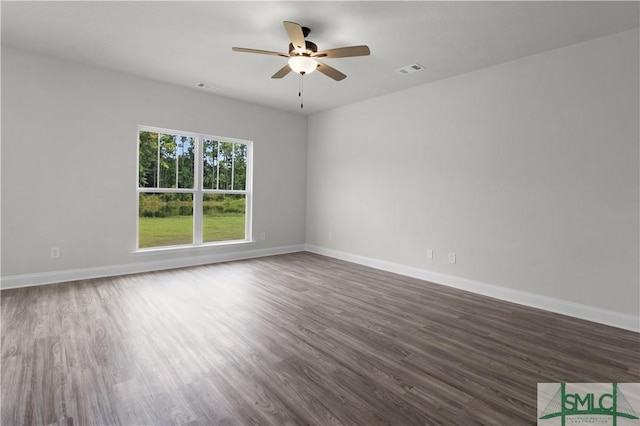 spare room featuring dark wood-type flooring, visible vents, baseboards, and a ceiling fan