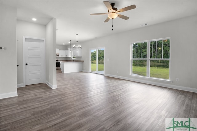 unfurnished living room featuring ceiling fan with notable chandelier and hardwood / wood-style floors