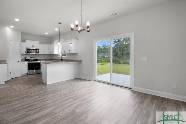 kitchen with appliances with stainless steel finishes, wood finished floors, visible vents, and baseboards