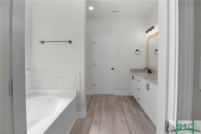 bathroom featuring a washtub, wood-type flooring, and vanity