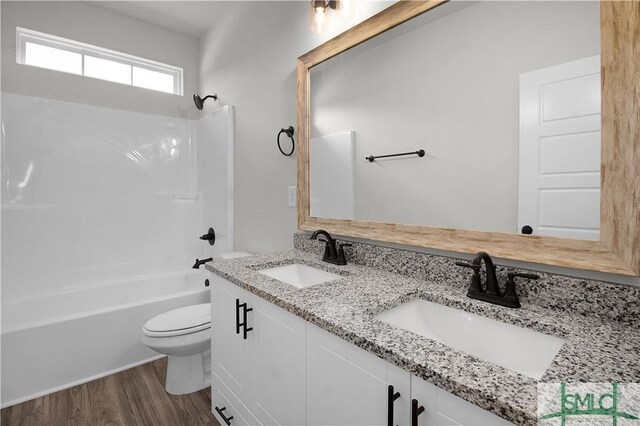 full bathroom featuring toilet, dual bowl vanity, hardwood / wood-style flooring, and shower / bath combination