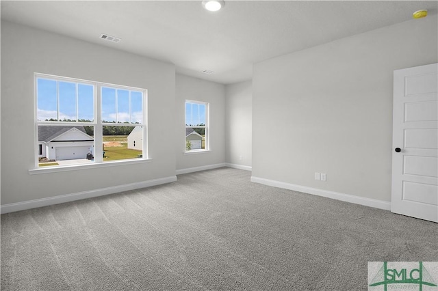 carpeted spare room with visible vents and baseboards