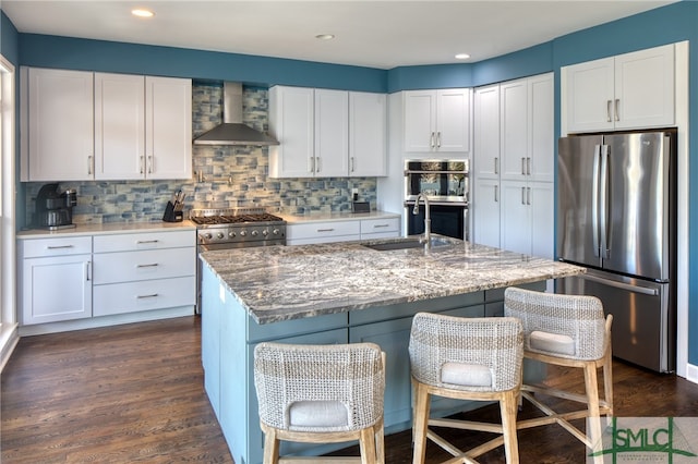 kitchen with a kitchen bar, white cabinetry, wall chimney exhaust hood, and stainless steel appliances