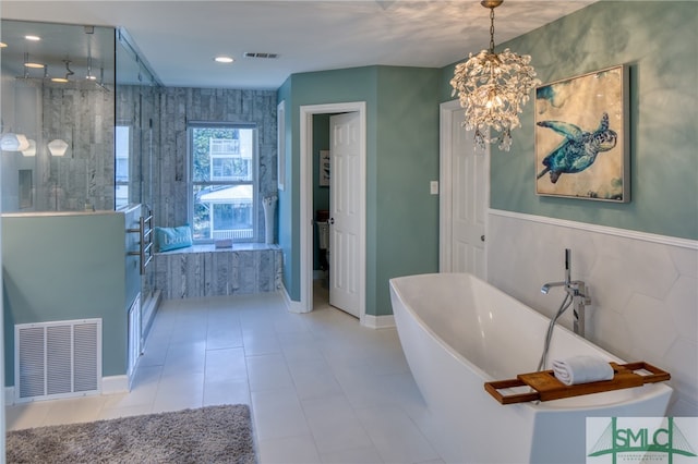 bathroom with tile walls, tile flooring, a chandelier, and a washtub