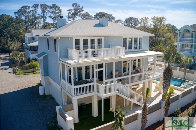 back of house with a balcony, a patio area, and a fenced in pool