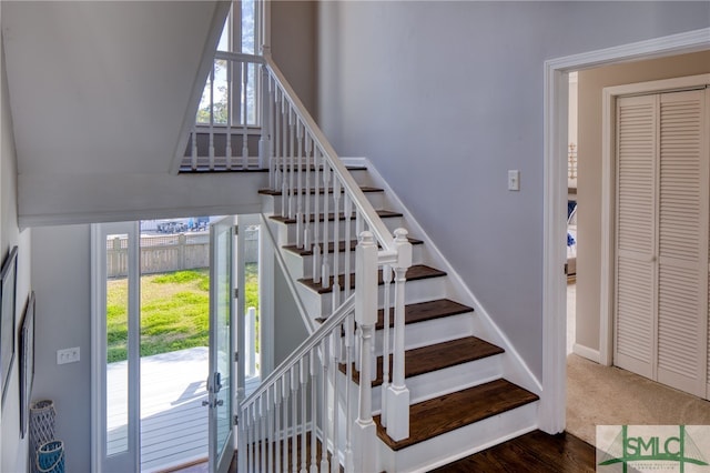 stairway with dark colored carpet and a healthy amount of sunlight