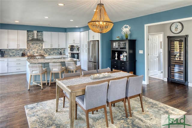 dining area with dark hardwood / wood-style flooring, an inviting chandelier, and sink