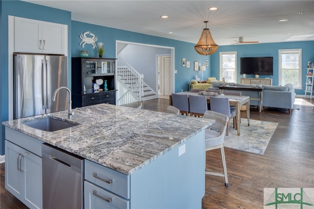 kitchen with dark wood-type flooring, stainless steel appliances, sink, a center island with sink, and white cabinets