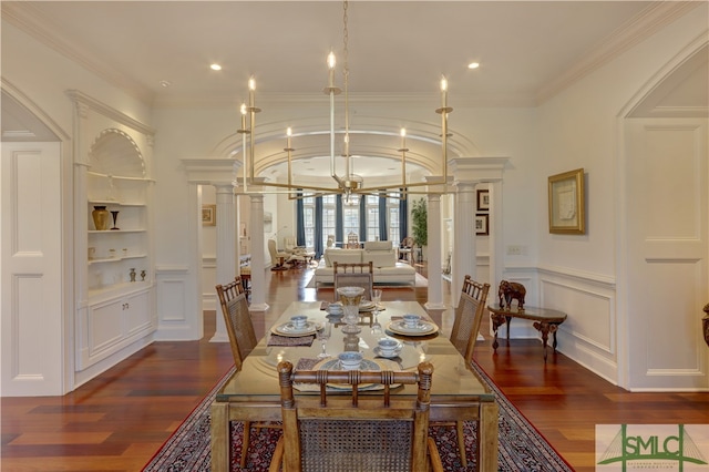 dining room featuring built in features, decorative columns, dark hardwood / wood-style floors, a notable chandelier, and ornamental molding