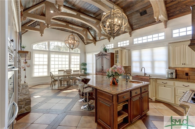 kitchen featuring light tile floors, wood ceiling, hanging light fixtures, a chandelier, and a kitchen island with sink