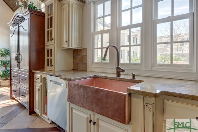 kitchen with cream cabinets, dishwasher, and light stone counters