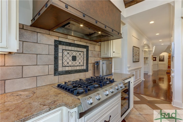 kitchen featuring premium range hood, stainless steel gas cooktop, white cabinetry, and light stone countertops