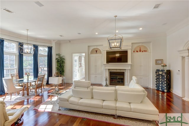 living room with ornamental molding, hardwood / wood-style flooring, and an inviting chandelier