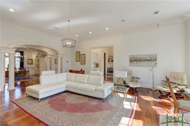 living room featuring ornamental molding, light hardwood / wood-style flooring, decorative columns, and an inviting chandelier