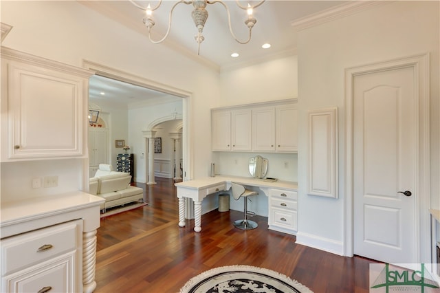 home office featuring crown molding, an inviting chandelier, built in desk, and dark hardwood / wood-style floors