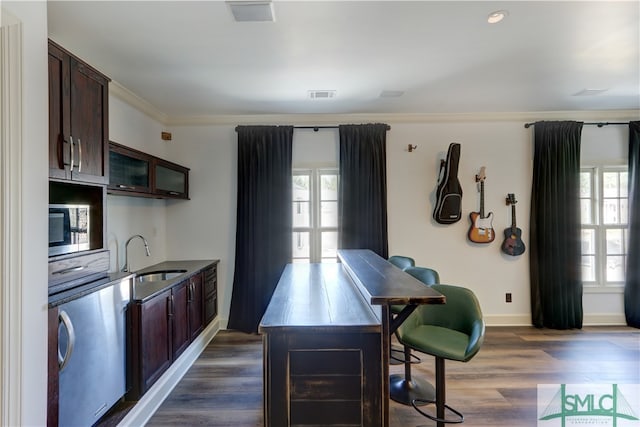 kitchen featuring dark brown cabinetry, sink, dark wood-type flooring, crown molding, and a kitchen breakfast bar