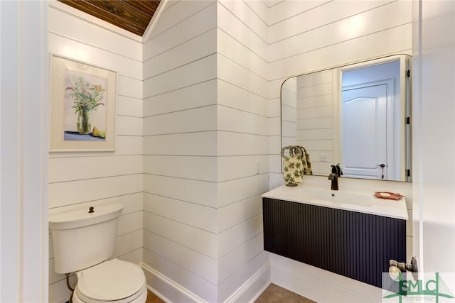 bathroom featuring wooden ceiling, vanity, wooden walls, and toilet