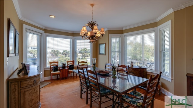 dining space featuring ornamental molding, a chandelier, and light hardwood / wood-style flooring