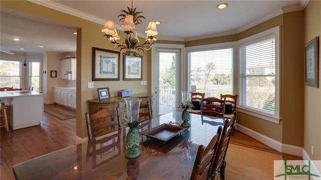 dining room with a chandelier, ornamental molding, and light wood-type flooring