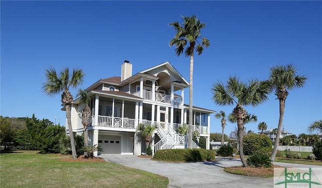 coastal home with a balcony, a front yard, and a garage