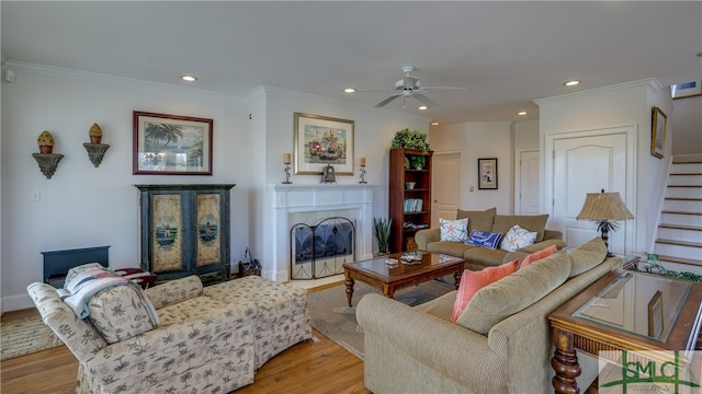 living room with ceiling fan, ornamental molding, and light hardwood / wood-style flooring