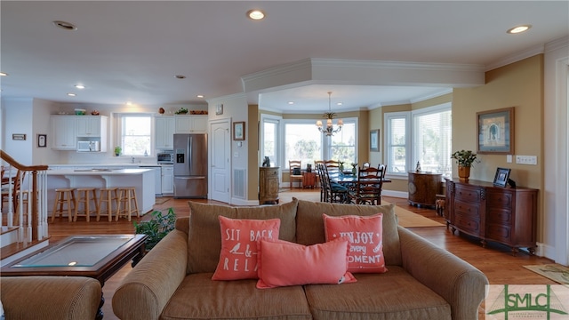 living room featuring a notable chandelier, crown molding, and light wood-type flooring