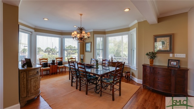 dining space with ornamental molding, a chandelier, and light hardwood / wood-style floors