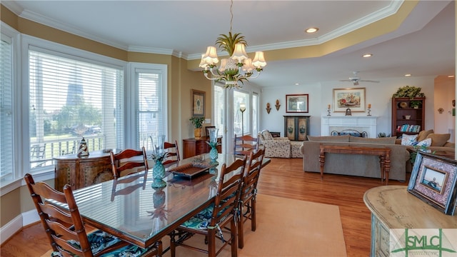 dining room with a wealth of natural light, ornamental molding, light hardwood / wood-style floors, and ceiling fan with notable chandelier