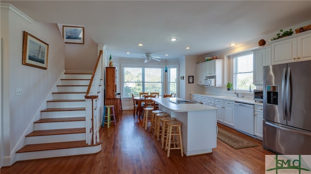 kitchen with white cabinetry, a breakfast bar, white dishwasher, stainless steel refrigerator with ice dispenser, and a kitchen island