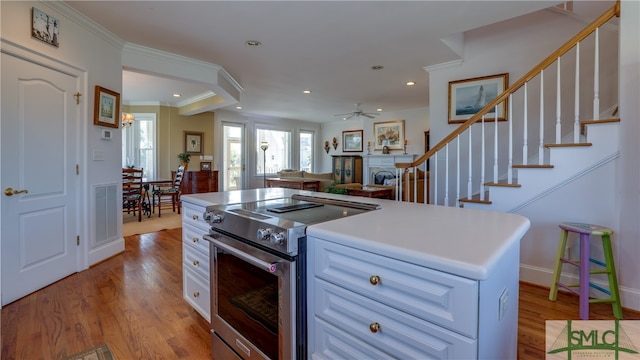 kitchen featuring white cabinetry, ceiling fan, light hardwood / wood-style floors, high end stainless steel range, and ornamental molding
