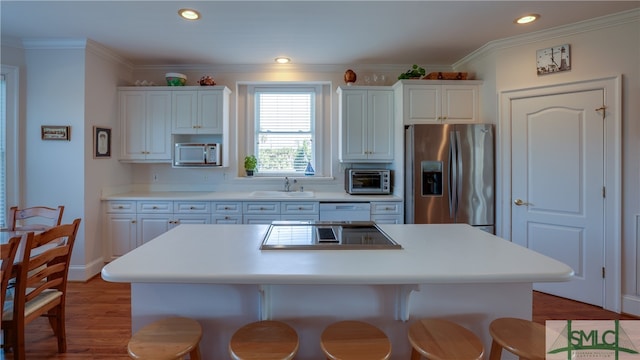 kitchen with hardwood / wood-style flooring, white cabinets, a breakfast bar area, stainless steel appliances, and sink